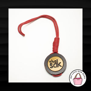 THE SAK GOLD BRASS BROWN WOOD DISC RED CORD KEY FOB BAG CHARM KEYCHAIN HANG TAG